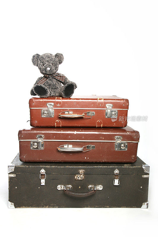 棕色的旧行李箱堆在一起，上面有熊