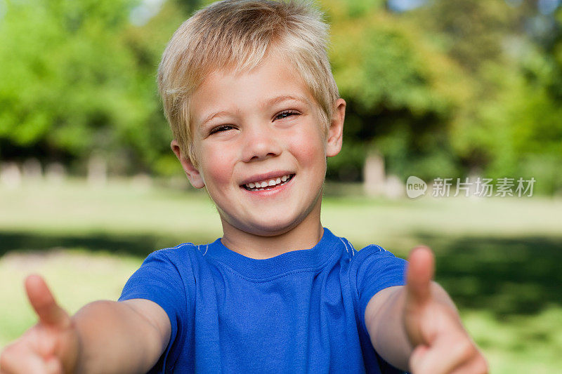 可爱的孩子在公园里竖起他的两个拇指