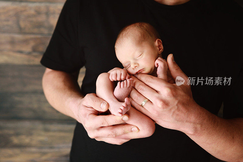 刚出生的婴儿睡在爸爸的怀里