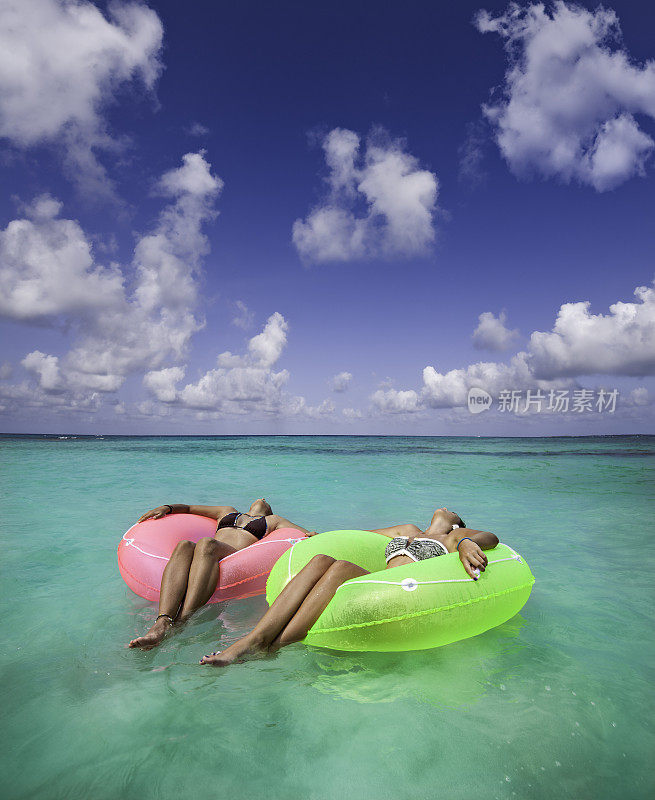 两个年轻女人放松与管在热带加勒比海滩