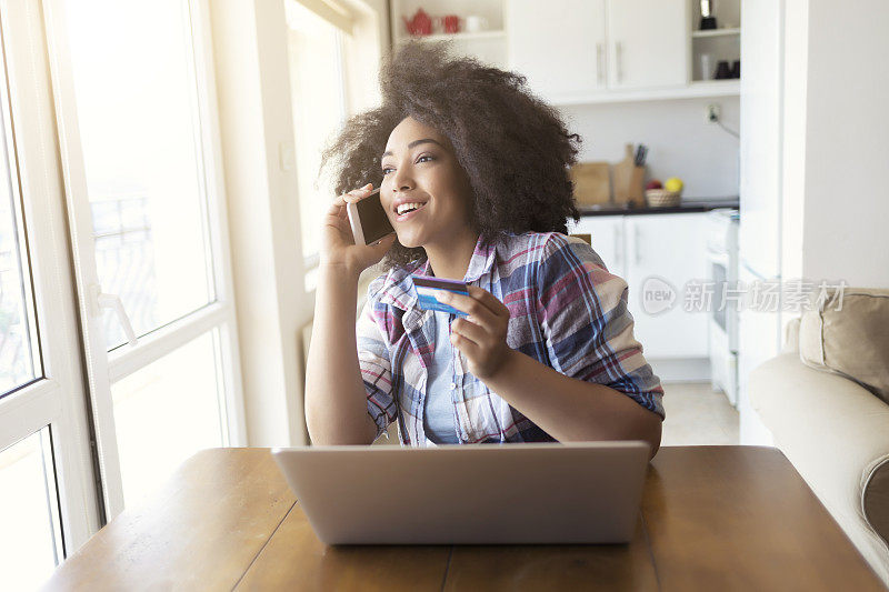 微笑的女人在家里使用信用卡和智能手机