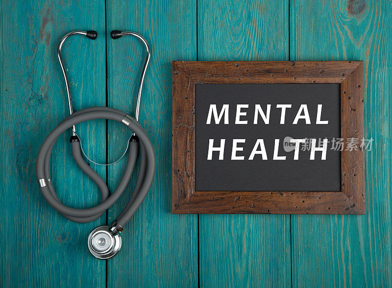 黑板上写着“心理健康”，听诊器以蓝色木制为背景
