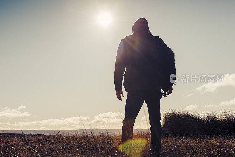 男人在秋日的阳光下徒步旅行。