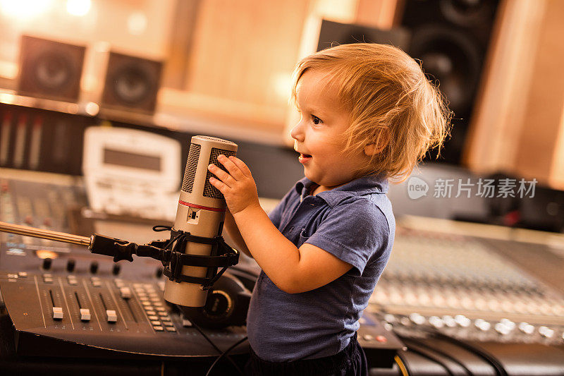一个快乐的小男孩在电台里对着麦克风说话。