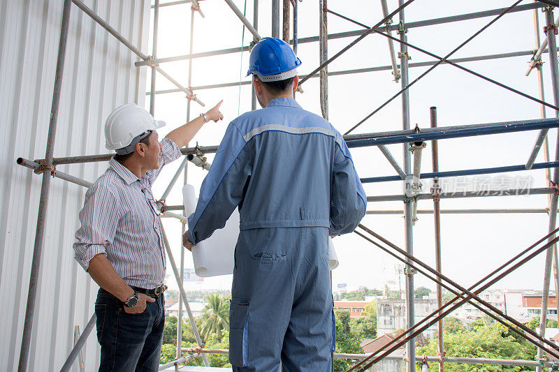 亚洲专业的工程团队戴着安全帽，指着施工项目