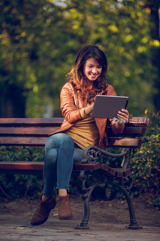 一个年轻女子在公园里拿着平板电脑