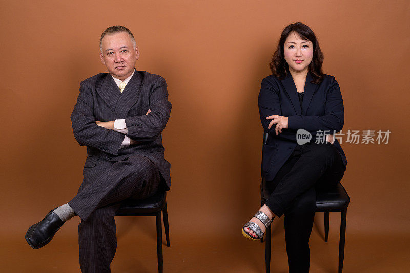 工作室拍摄了两个成熟的亚洲商人和女商人的彩色背景