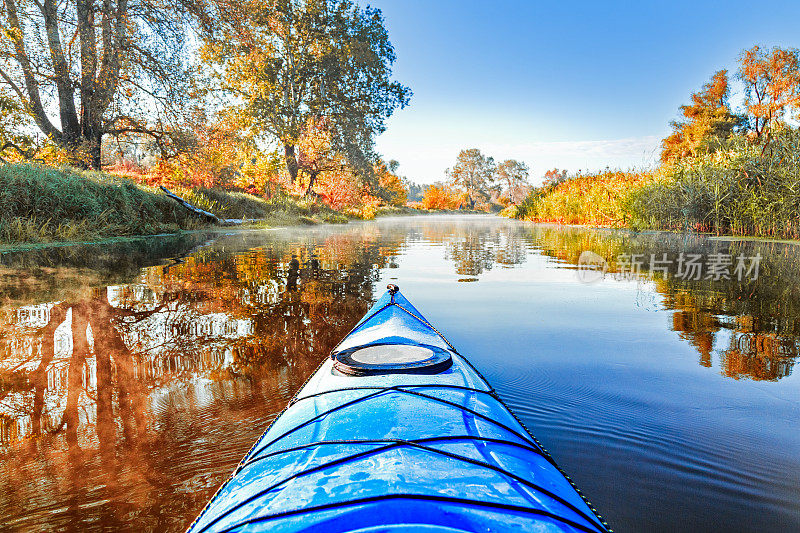 从蓝色的皮艇在河岸与秋天的黄叶树秋天季节。塞夫斯基顿涅茨河，秋季皮划艇。在亮蓝色皮艇的鼻子上方的视图。