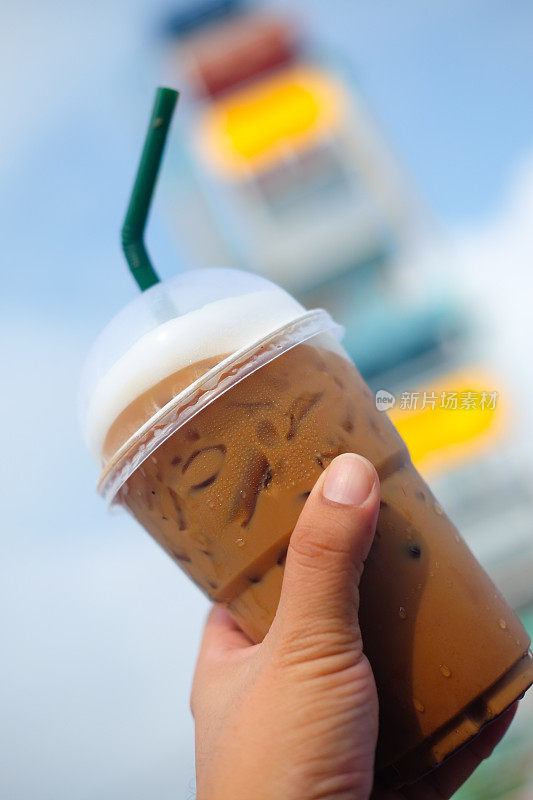 冰咖啡在塑料玻璃与游乐园背景