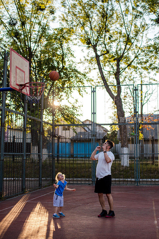 年轻的千禧一代父亲和他的小女儿打篮球