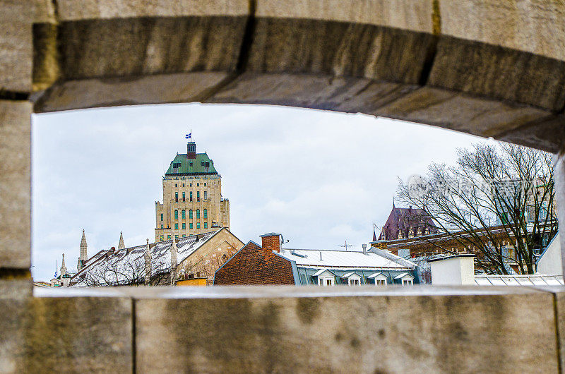 在冬天的白天，通过圣。约翰的大门上的墙洞看到魁北克市中心