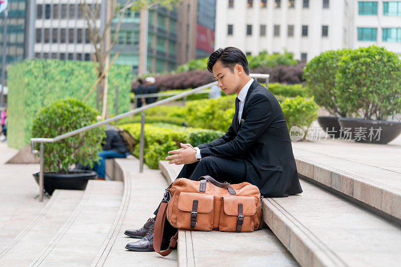 年轻愁眉苦脸的商人坐在户外