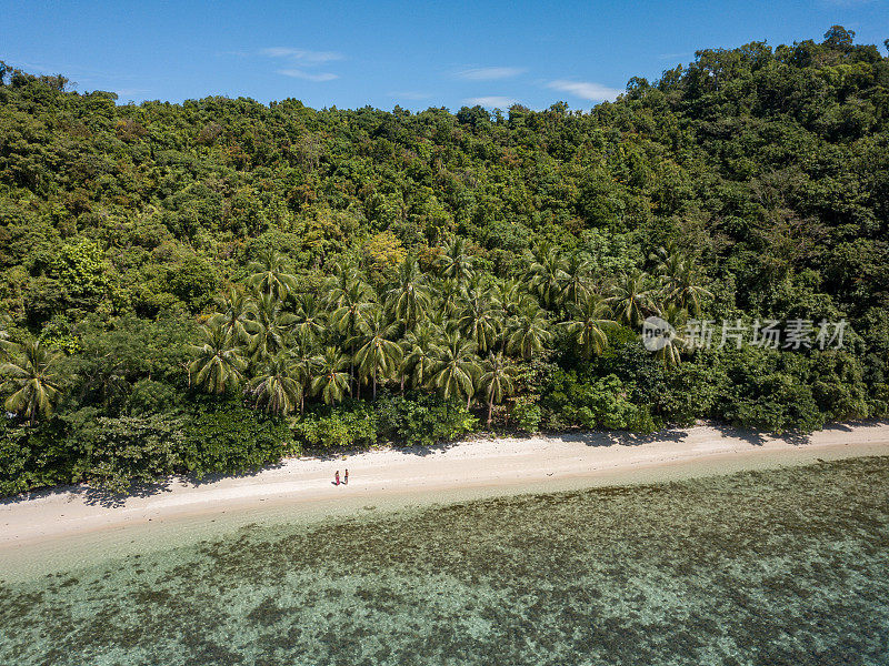 这是一对年轻夫妇在菲律宾群岛一个美丽的泻湖的热带海滩上放松的无人机鸟瞰图。人们旅行豪华度假目的地的概念