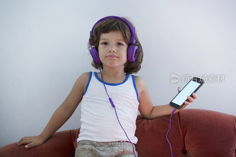 小男孩在用智能手机听音乐。