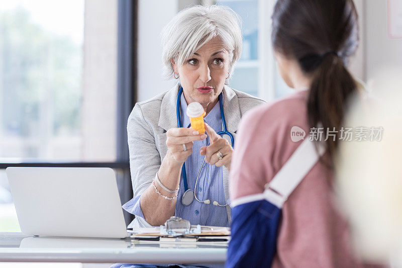 一位大四的医疗顾问拿着一个药瓶，她正在和一位女病人谈话