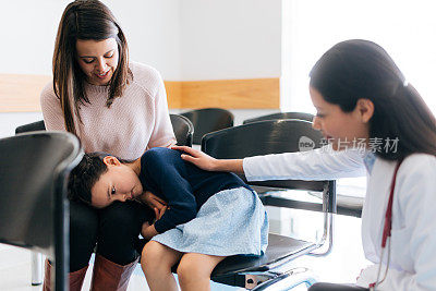 女孩头枕在妈妈的膝盖上，旁边是医生