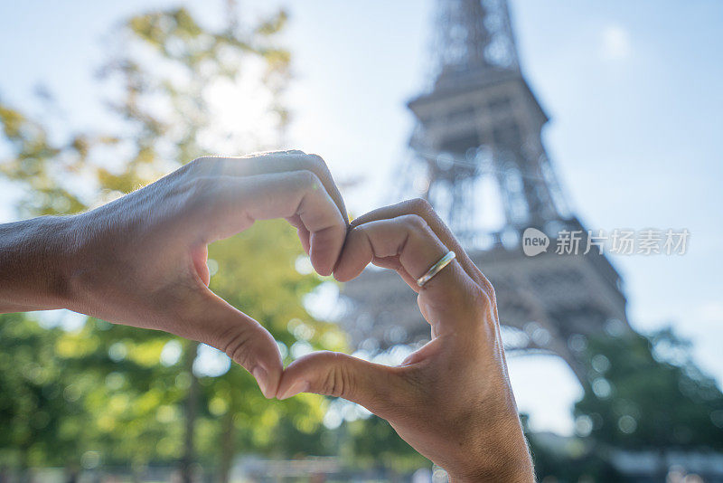 一个热爱巴黎旅游的年轻女子在春天的埃菲尔铁塔上做了一个心形的雕塑