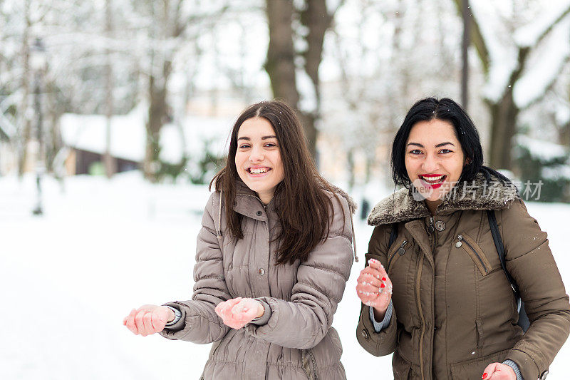 快乐的妈妈和女儿在雪中玩耍