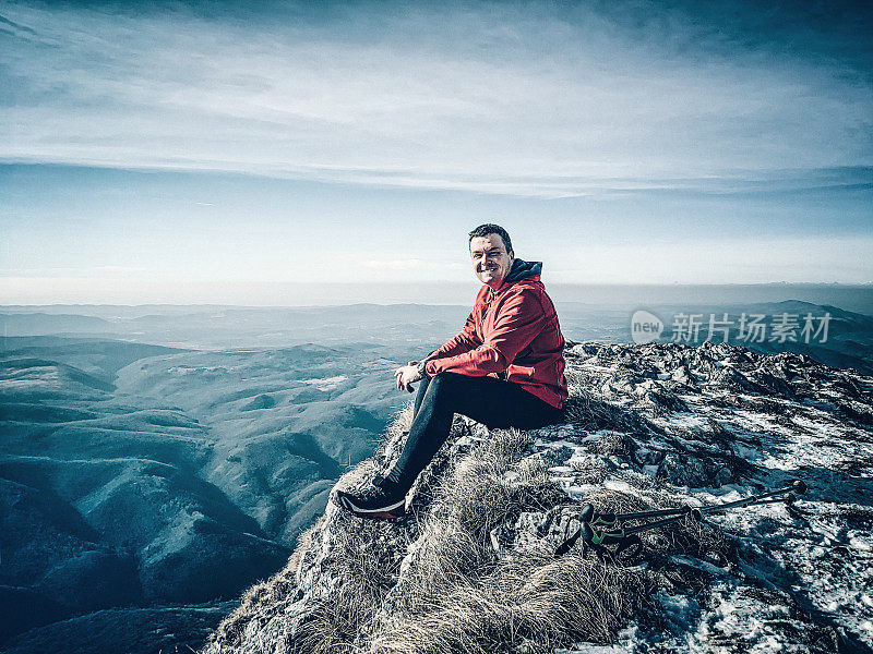 快乐的登山运动员坐在山顶上