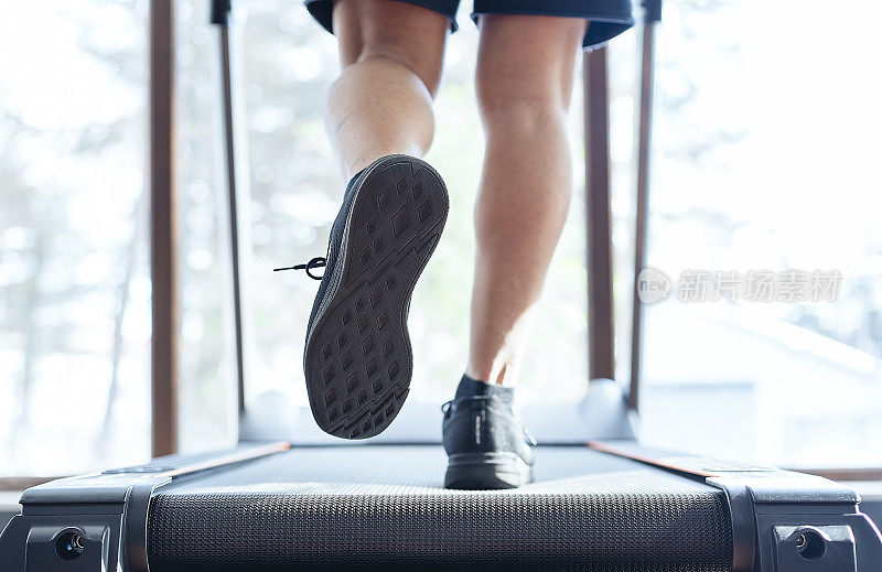 健身教练慢跑在跑步机上-近距离拍摄的脚在健康俱乐部