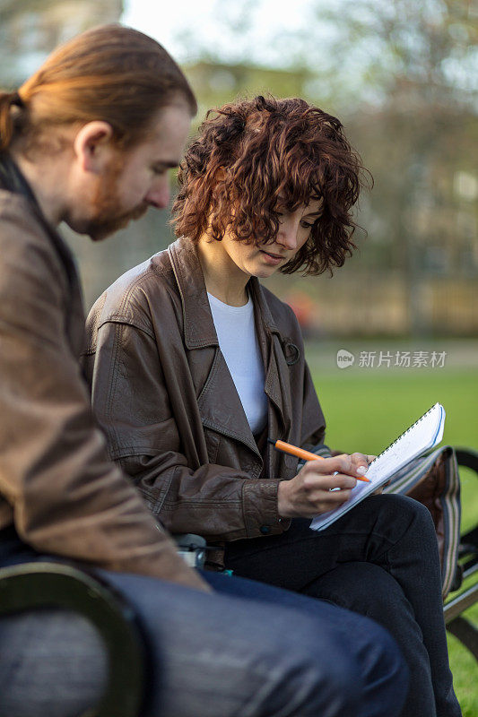 女人在和朋友一起学习时做笔记
