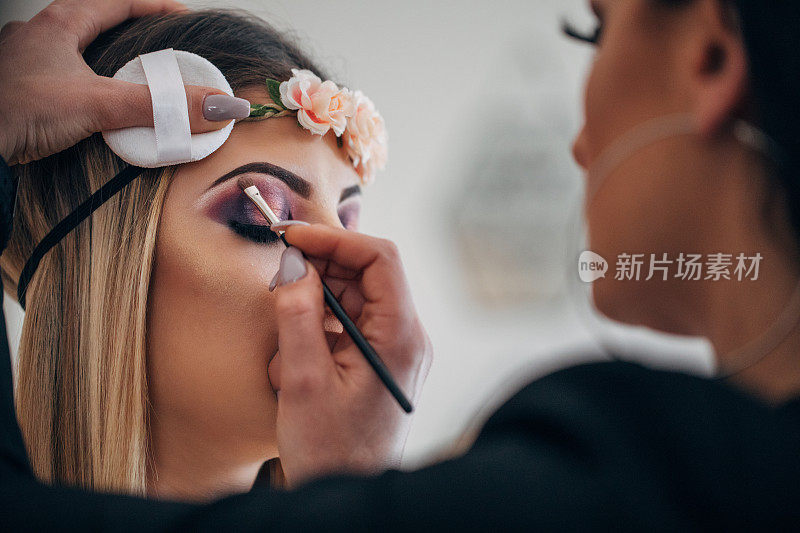 化妆师正在给一个漂亮女孩上眼妆