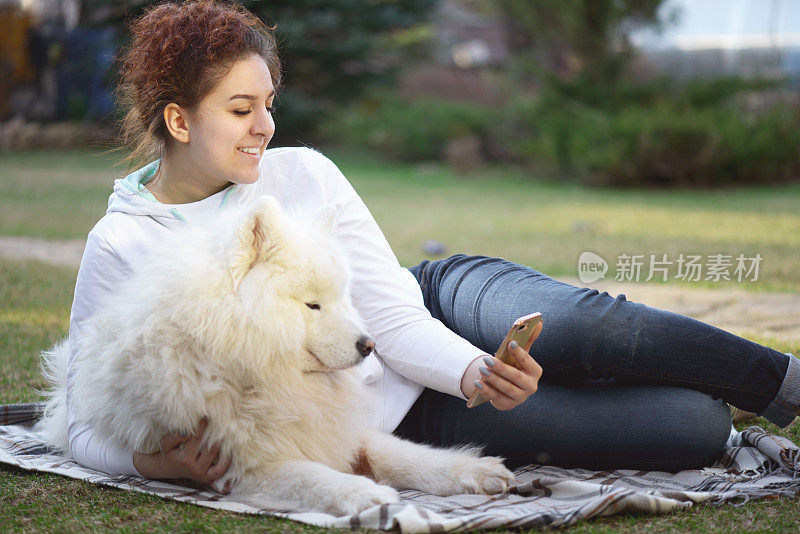 女人和萨摩耶狗(夏天，智能手机)