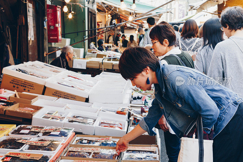 年轻的亚洲女游客和日本人像往常一样在东京筑地鱼市购物和旅游，