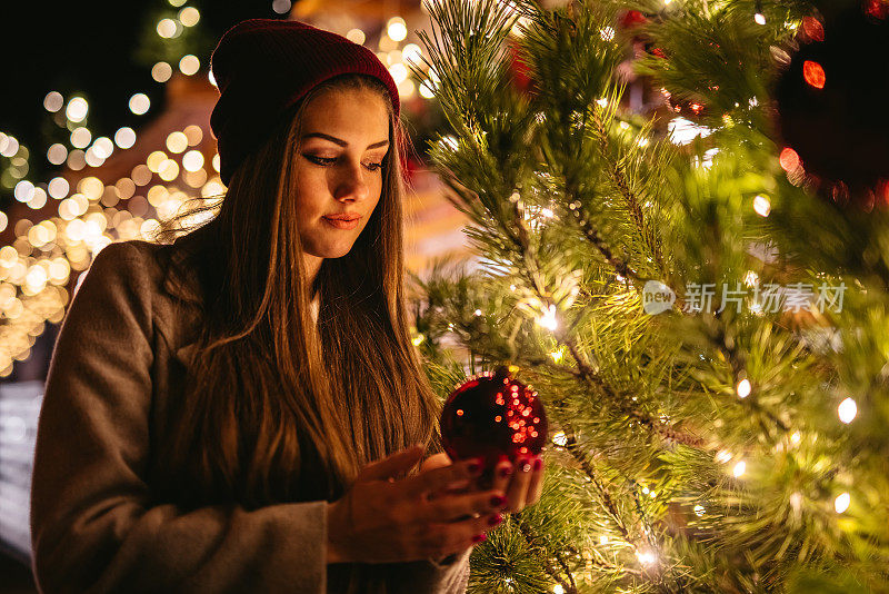 一名年轻女子站在户外的圣诞树旁