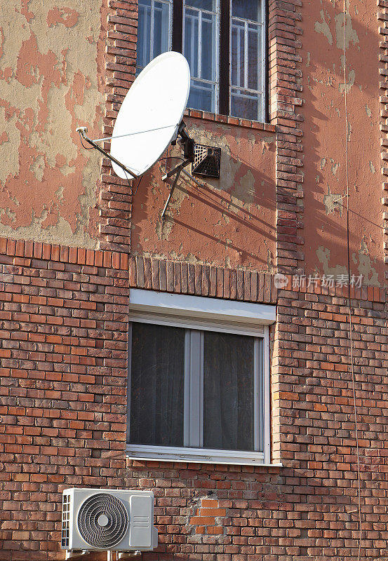卫星天线和空调安装在一栋旧公寓楼的墙上