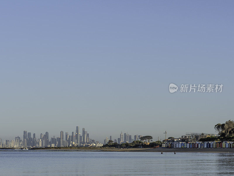 清晨的海滩小屋和城市天际线