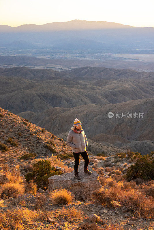 一位年长的妇女站在山顶上看日落