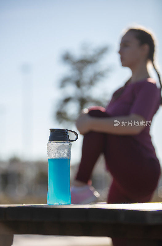 年轻女子在户外运动期间在外面补水。