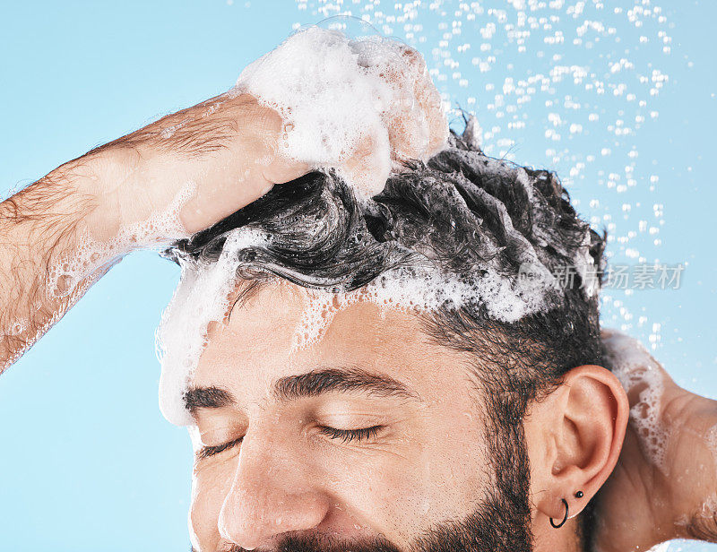 脸，水溅和人在淋浴与洗发水在工作室在蓝色背景。皮肤护理皮肤科，水滴和男模清洁，洗澡或洗头发护理，卫生和健康。