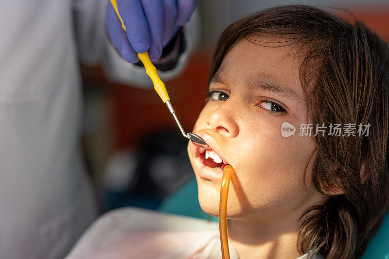 一个嘴里含着硅胶管的男孩在等着修复他的断牙