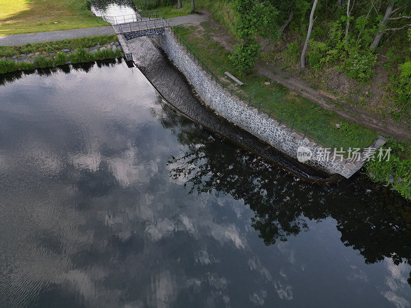 跨越大坝安全溢洪道的桥梁。石桥用天然的灰色石板铺装。挡土墙的边缘是一个微妙的彩色锻铁栏杆。水从下面流过