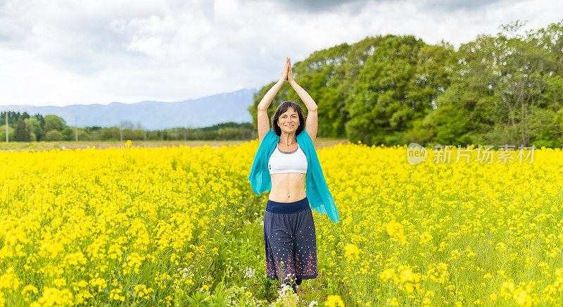 一位女士在黄色的油菜花地里练习瑜伽，放松身心