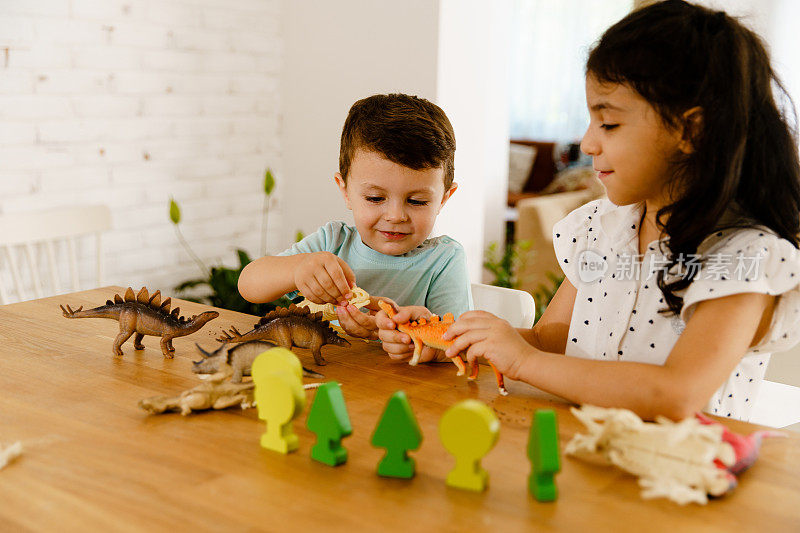 好奇的孩子们在桌子上玩恐龙玩具