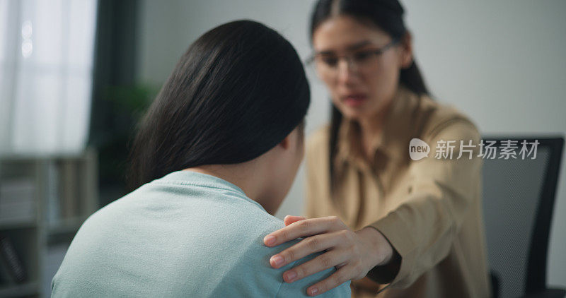 年轻的专业治疗师一边哭泣一边抚摸女病人的肩膀