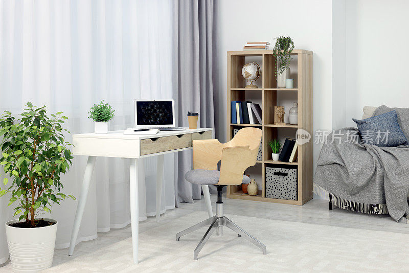 工作场所，桌子上有现代化的笔记本电脑，家里有舒适的椅子