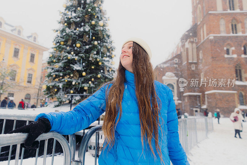 快乐的女人背着背包，在克拉科夫思考下雪的圣诞节