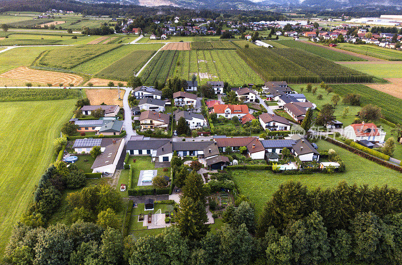 鸟瞰图，一个郊区社区的房子和绿色草坪，旁边是开阔的田野和道路。