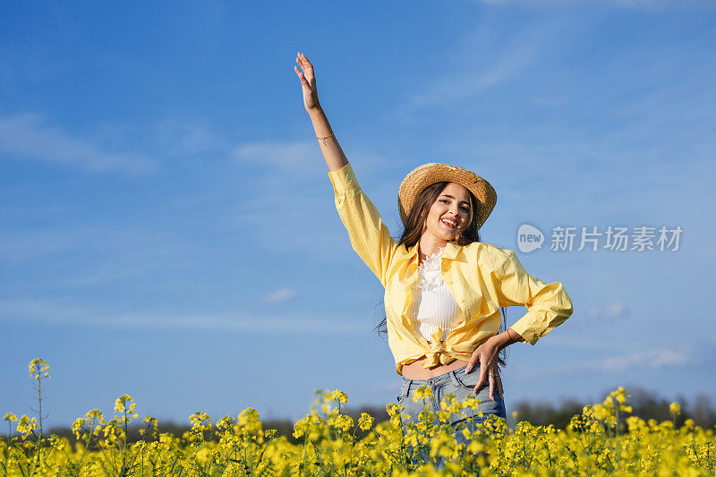 美丽的年轻女子在油菜籽地里享受着无忧无虑的春日