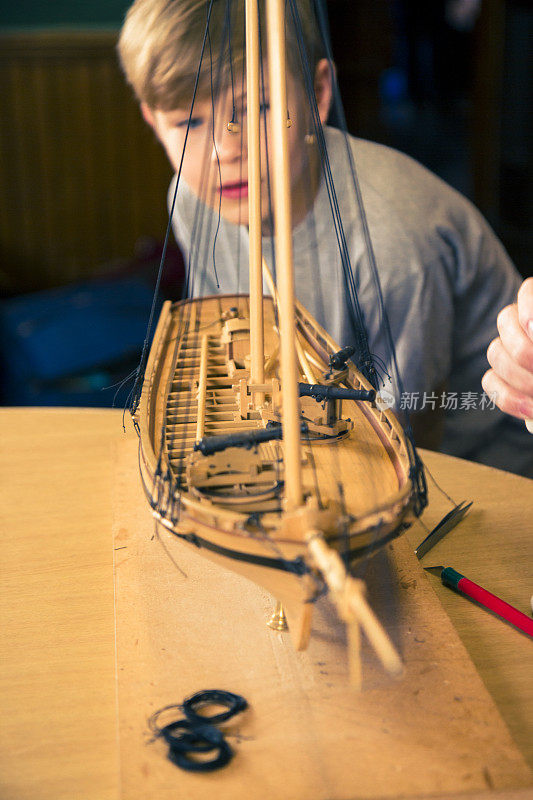 男孩在教室里看着一个造船模型制造者工作