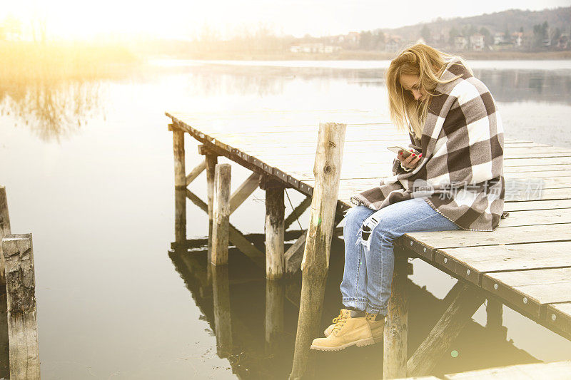 年轻女子在湖边与智能手机放松