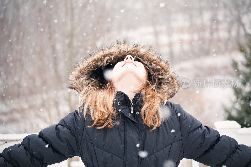 年轻女孩仰望着飘落的雪花