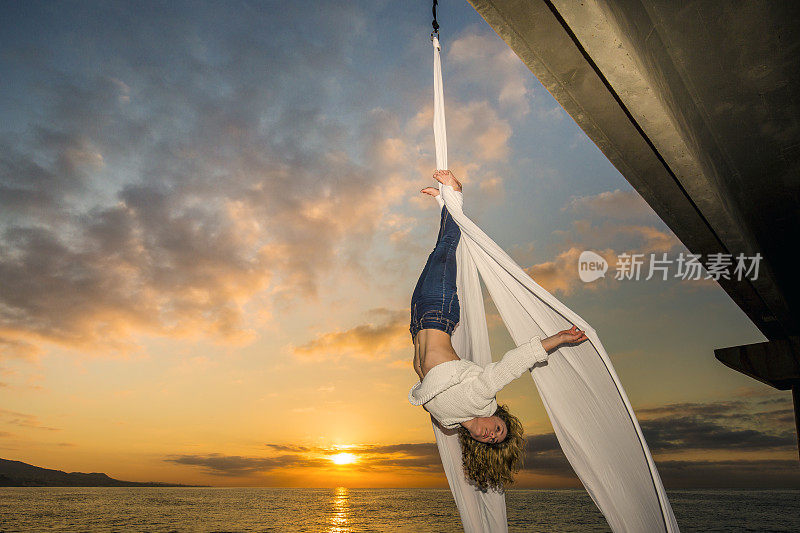 海上日出时空中的女丝绸舞者