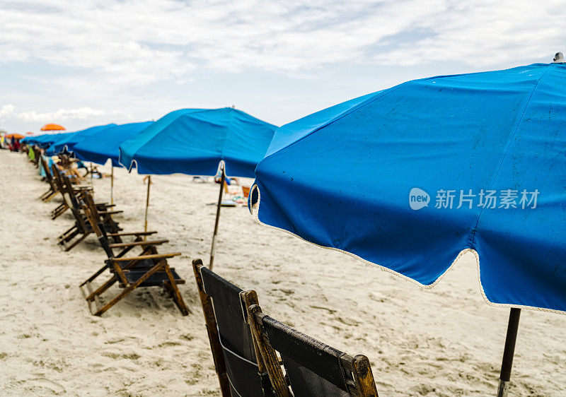 沙滩椅和雨伞在海边一字排开