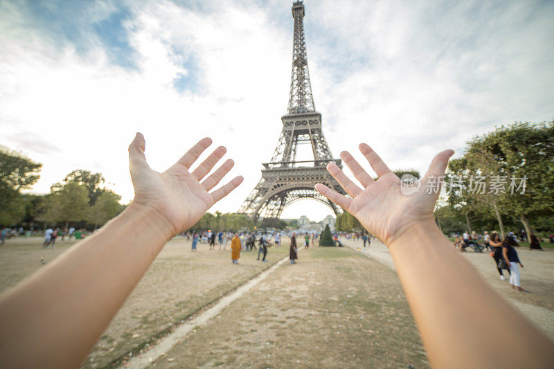 一位女士的手臂伸向法国巴黎的埃菲尔铁塔