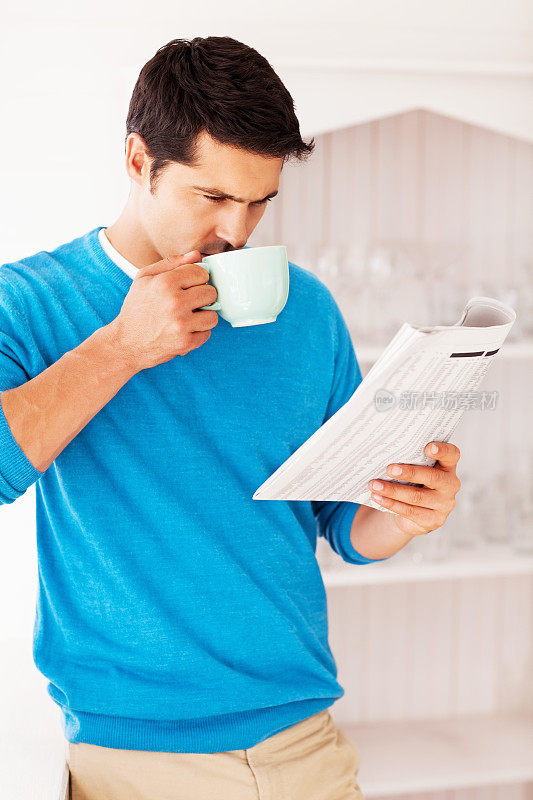 一边看报纸一边喝咖啡的男人